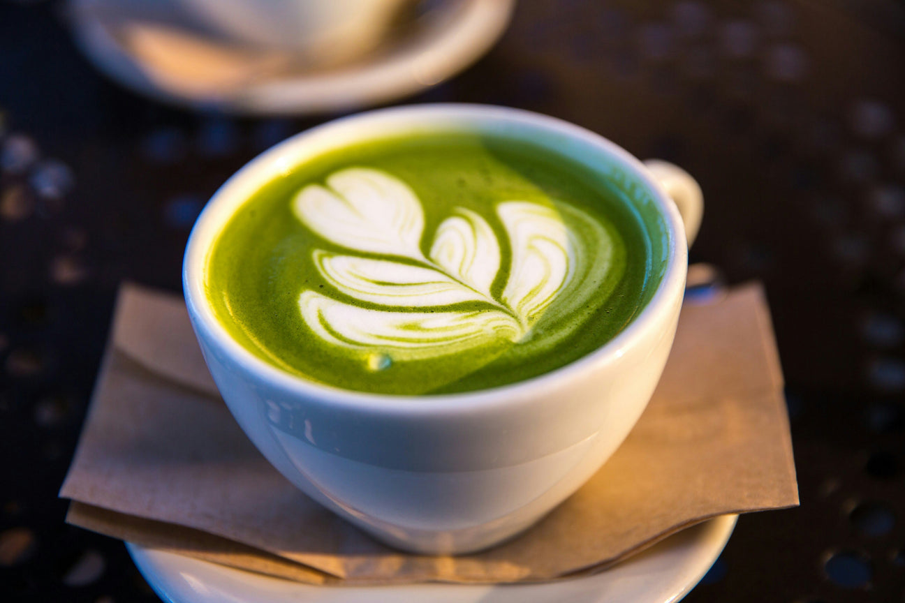 Ceremonial matcha latte with leaf latte art in a white cup on a saucer