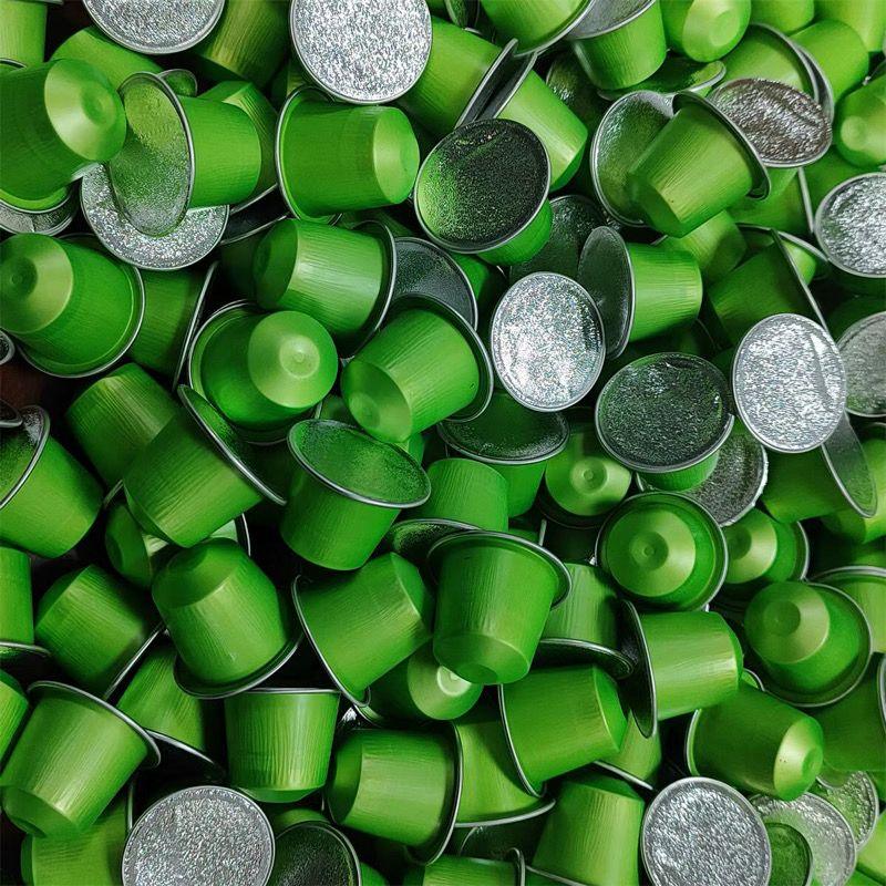 Pile of green matcha capsules with silver foil tops, ideal for single-serve matcha drinks