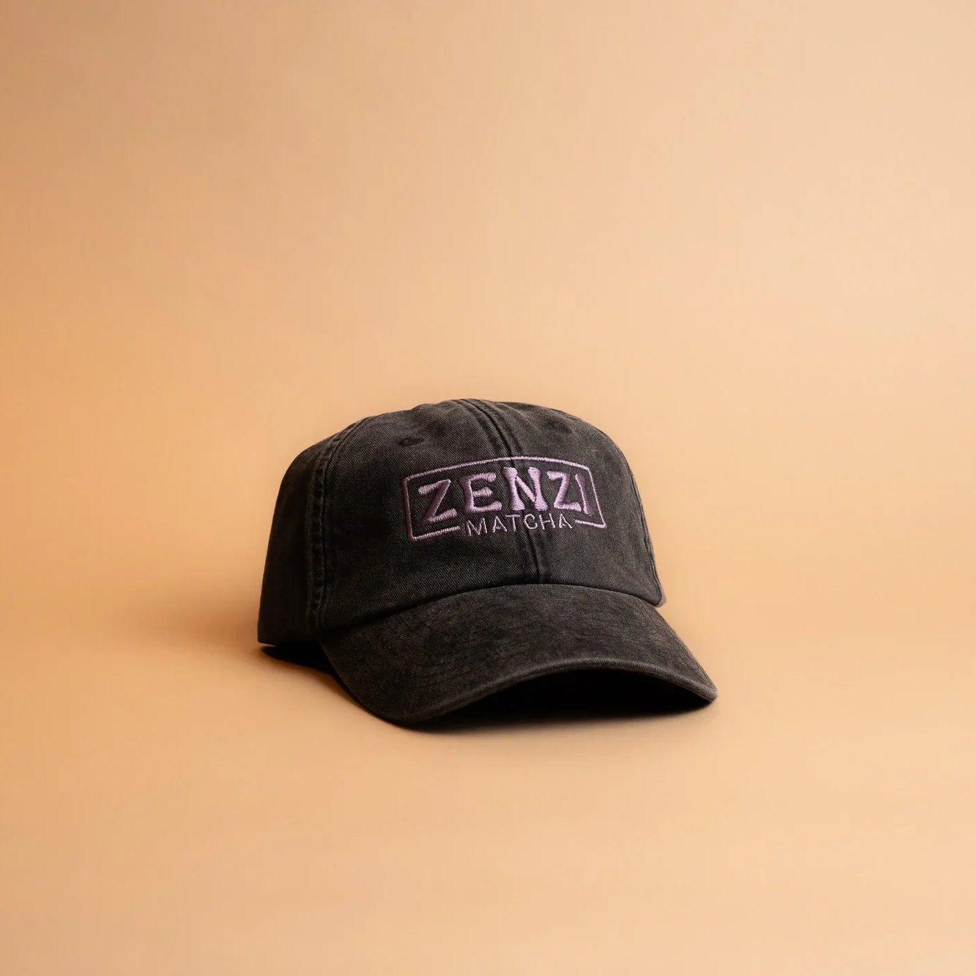 Black Zenzi Matcha cap with embroidered logo on beige background